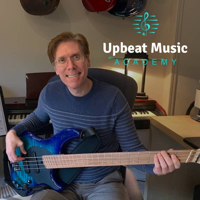 Bass Lesson with Noel Wentworth at the Upbeat Music Academy Kelowna Noel Wentworth holds a Bass guitar on his lap at his Upbeat Music Academy Kelowna Studio.